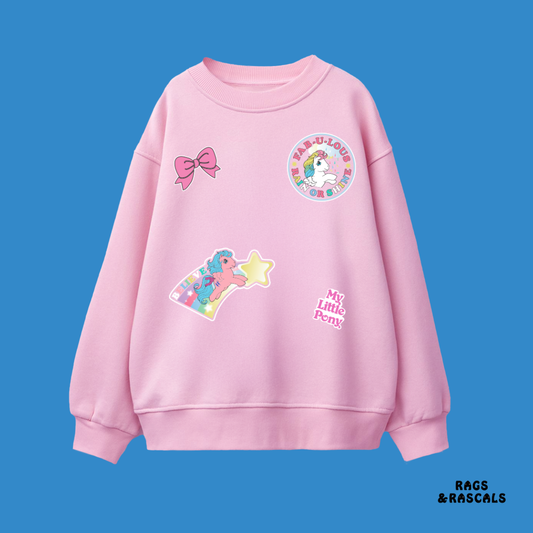 Pink sweatshirt with colorful patches pony and stickers, from a children's brand called "Rags and Rascals".